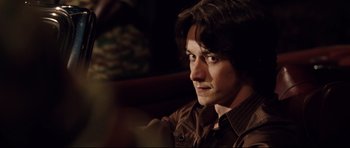 Movie still from “The Last King of Scotland” (2006), directed by Kevin Macdonald – A person sitting in a room; Close Up shot, Over the shoulder angle