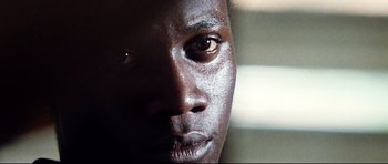 Movie still from “The Last King of Scotland” (2006), directed by Kevin Macdonald – A man's face with a dark background; Extreme Close Up shot, Low angle