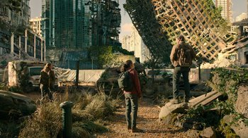 Movie still from “The Last of Us” (2023), created by Neil Druckmann – Two people standing on a dirt path near a building; Wide shot, Low angle