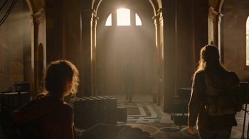 Movie still from “The Last of Us” (2023), created by Neil Druckmann – A man walking through a hallway in a building; Wide shot, Over the shoulder angle
