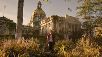 Movie still from “The Last of Us” (2023), created by Neil Druckmann – A man standing in front of an abandoned building; Extreme Wide shot, Low angle