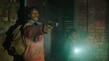 Movie still from “The Last of Us” (2023), created by Neil Druckmann – A man pointing a gun at a woman; Medium shot, Over the shoulder angle