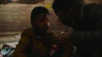 Movie still from “The Last of Us” (2023), created by Neil Druckmann – A young boy is being painted by an older man; Close Up shot, Over the shoulder angle