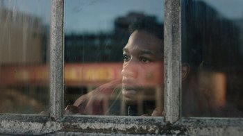 Movie still from “The Last of Us” (2023), created by Neil Druckmann – A man looking out of a window at the street; Close Up shot, Low angle
