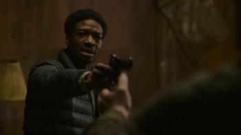 Movie still from “The Last of Us” (2023), created by Neil Druckmann – A man holding a gun up to his face; Close Up shot, Low angle