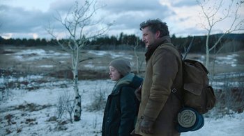 Movie still from “The Last of Us” (2023), created by Neil Druckmann – A man and a woman standing next to each other in the snow; Medium shot, Over the shoulder angle