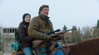 Movie still from “The Last of Us” (2023), created by Neil Druckmann – A man and a woman riding on a horse with a rifle; Medium shot, Low angle
