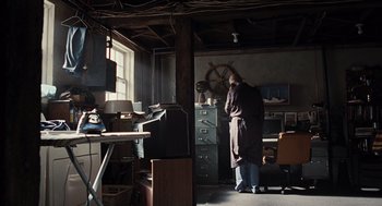 Movie still from “Burn After Reading” (2008), directed by Joel Coen – A man standing in front of an open window in a room; Wide shot, Low angle