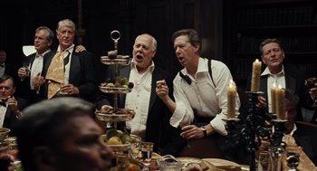 Movie still from “Burn After Reading” (2008), directed by Joel Coen – A group of people standing around a table with plates of food on it; Medium shot, High angle