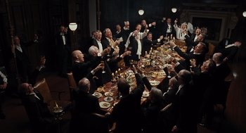 Movie still from “Burn After Reading” (2008), directed by Joel Coen – A group of men sitting around a dinner table; Wide shot, High angle