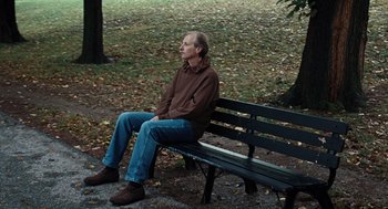 Movie still from “Burn After Reading” (2008), directed by Joel Coen – A man sitting on top of a wooden park bench; Medium shot, High angle