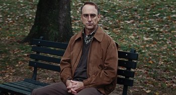 Movie still from “Burn After Reading” (2008), directed by Joel Coen – A man sitting on top of a wooden park bench; Medium shot, Over the shoulder angle