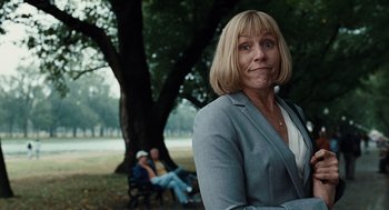 Movie still from “Burn After Reading” (2008), directed by Joel Coen – A woman in a gray jacket is posing for a picture; Close Up shot, Low angle