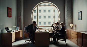 Movie still from “Burn After Reading” (2008), directed by Joel Coen – A group of people sitting at a table in front of a window; Wide shot, Over the shoulder angle