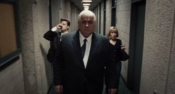 Movie still from “Burn After Reading” (2008), directed by Joel Coen – A man and two women in suits in a hallway; Medium shot, Low angle