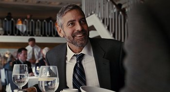 Movie still from “Burn After Reading” (2008), directed by Joel Coen – A person sitting at a table with a glass of wine; Close Up shot, Over the shoulder angle