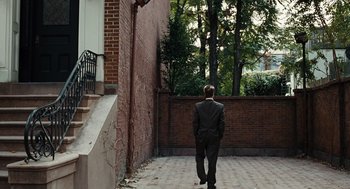 Movie still from “Burn After Reading” (2008), directed by Joel Coen – A man in a suit walking down a brick walkway; Extreme Wide shot, Over the shoulder angle