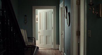 Movie still from “Burn After Reading” (2008), directed by Joel Coen – A white door leading to a room with a blue wall; Wide shot, High angle