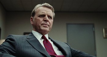 Movie still from “Burn After Reading” (2008), directed by Joel Coen – An older man in a suit and red tie; Close Up shot, Low angle