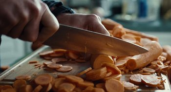 Movie still from “Burn After Reading” (2008), directed by Joel Coen – A person is cutting sweet potatoes on a cutting board; Extreme Close Up shot, High angle