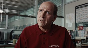 Movie still from “Burn After Reading” (2008), directed by Joel Coen – An older man in a red shirt is looking at the camera; Close Up shot, Over the shoulder angle