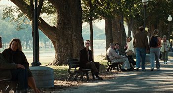 Movie still from “Burn After Reading” (2008), directed by Joel Coen – A group of people sitting on park benches near a tree; Wide shot, Over the shoulder angle