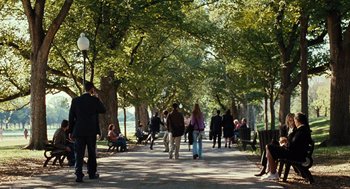 Movie still from “Burn After Reading” (2008), directed by Joel Coen – A group of people walking down a tree lined sidewalk; Extreme Wide shot, Over the shoulder angle