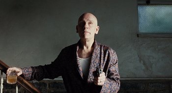 Movie still from “Burn After Reading” (2008), directed by Joel Coen – A bald man holding a gun in his right hand; Medium shot, Low angle