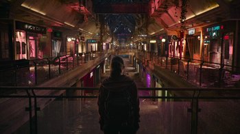 Movie still from “The Last of Us” (2023), created by Neil Druckmann – A person with a backpack is standing in an empty shopping mall; Extreme Wide shot, High angle