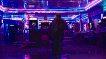 Movie still from “The Last of Us” (2023), created by Neil Druckmann – A person standing in a room with neon lights; Wide shot, Low angle