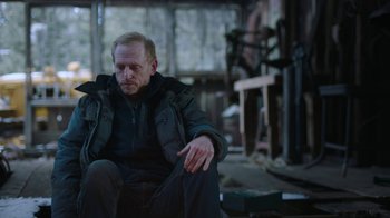 Movie still from “The Last of Us” (2023), created by Neil Druckmann – A man sitting on the ground in a room; Medium shot, Over the shoulder angle