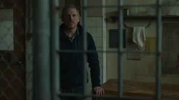 Movie still from “The Last of Us” (2023), created by Neil Druckmann – A man standing behind bars in a jail cell; Medium shot, Low angle