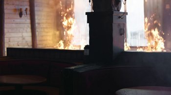 Movie still from “The Last of Us” (2023), created by Neil Druckmann – A fire is burning in the background of a fireplace; Medium shot, Low angle