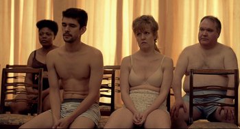 Movie still from “The Lobster” (2015), directed by Yorgos Lanthimos – A woman and a man sitting next to each other in their underwear; Medium shot, Over the shoulder angle