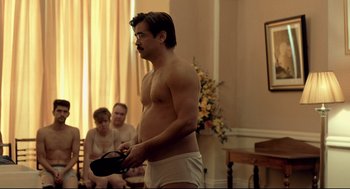 Movie still from “The Lobster” (2015), directed by Yorgos Lanthimos – A man with no shirt standing in front of two other men; Medium shot, Over the shoulder angle