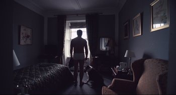 Movie still from “The Lobster” (2015), directed by Yorgos Lanthimos – A man standing next to a dog in a room; Wide shot, Low angle