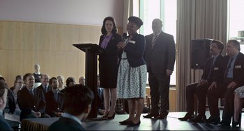 Movie still from “The Lobster” (2015), directed by Yorgos Lanthimos – Two women and a man standing in front of a microphone; Wide shot, Over the shoulder angle