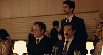 Movie still from “The Lobster” (2015), directed by Yorgos Lanthimos – A group of men in suits and ties sitting at a table; Medium shot, Over the shoulder angle