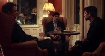 Movie still from “The Lobster” (2015), directed by Yorgos Lanthimos – A man sitting in a chair with a glass of whiskey; Medium shot, Over the shoulder angle