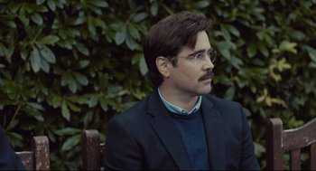 Movie still from “The Lobster” (2015), directed by Yorgos Lanthimos – A man sitting on top of a wooden bench next to a bush; Close Up shot, Over the shoulder angle