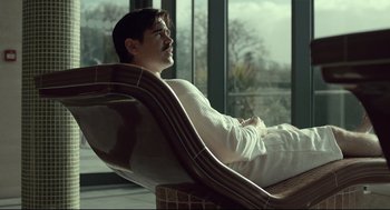 Movie still from “The Lobster” (2015), directed by Yorgos Lanthimos – A man sitting in a chair looking out a window; Medium shot, Low angle