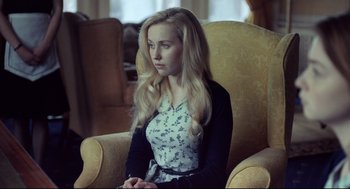 Movie still from “The Lobster” (2015), directed by Yorgos Lanthimos – A woman sitting in a chair in a living room; Medium shot, Over the shoulder angle