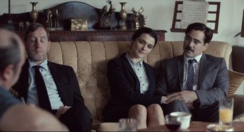 Movie still from “The Lobster” (2015), directed by Yorgos Lanthimos – A woman sitting on a couch next to two other people; Medium shot, Over the shoulder angle