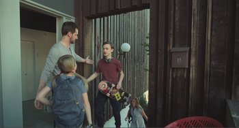 Movie still from “The Lodge” (2019), directed by Severin Fiala – A group of young people standing around a building; Wide shot, Over the shoulder angle
