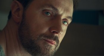 Movie still from “The Lodge” (2019), directed by Severin Fiala – A man with a beard looking at the camera; Extreme Close Up shot, Low angle