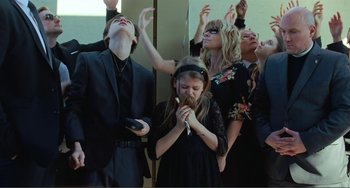Movie still from “The Lodge” (2019), directed by Severin Fiala – A group of people standing around each other in a room; Medium shot, Low angle
