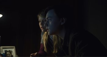 Movie still from “The Lodge” (2019), directed by Severin Fiala – A couple of people sitting in a dark room; Close Up shot, Low angle