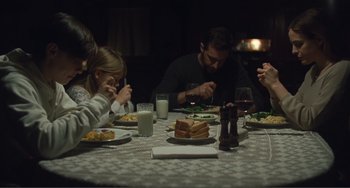 Movie still from “The Lodge” (2019), directed by Severin Fiala – A group of people sitting at a dinner table eating food; Medium shot, Low angle
