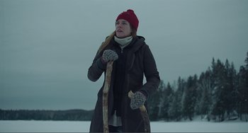 Movie still from “The Lodge” (2019), directed by Severin Fiala – A woman holding a pair of skis in the snow; Medium shot, Low angle
