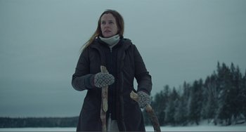 Movie still from “The Lodge” (2019), directed by Severin Fiala – A woman in a black jacket holding a pair of skis; Medium shot, Low angle